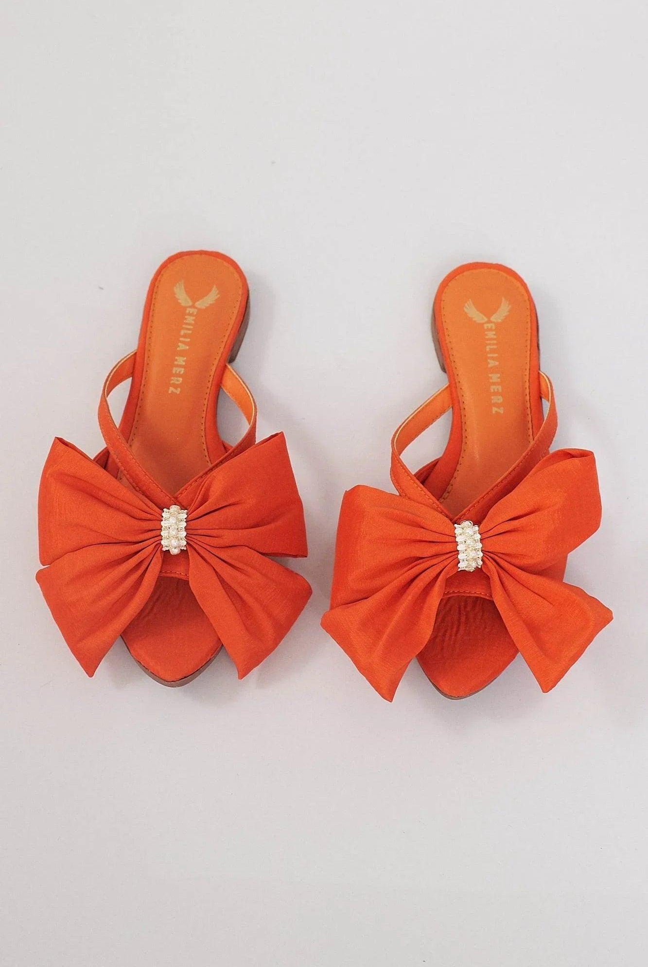 Orange slide sandals with large bow and pearl embellishment on white background