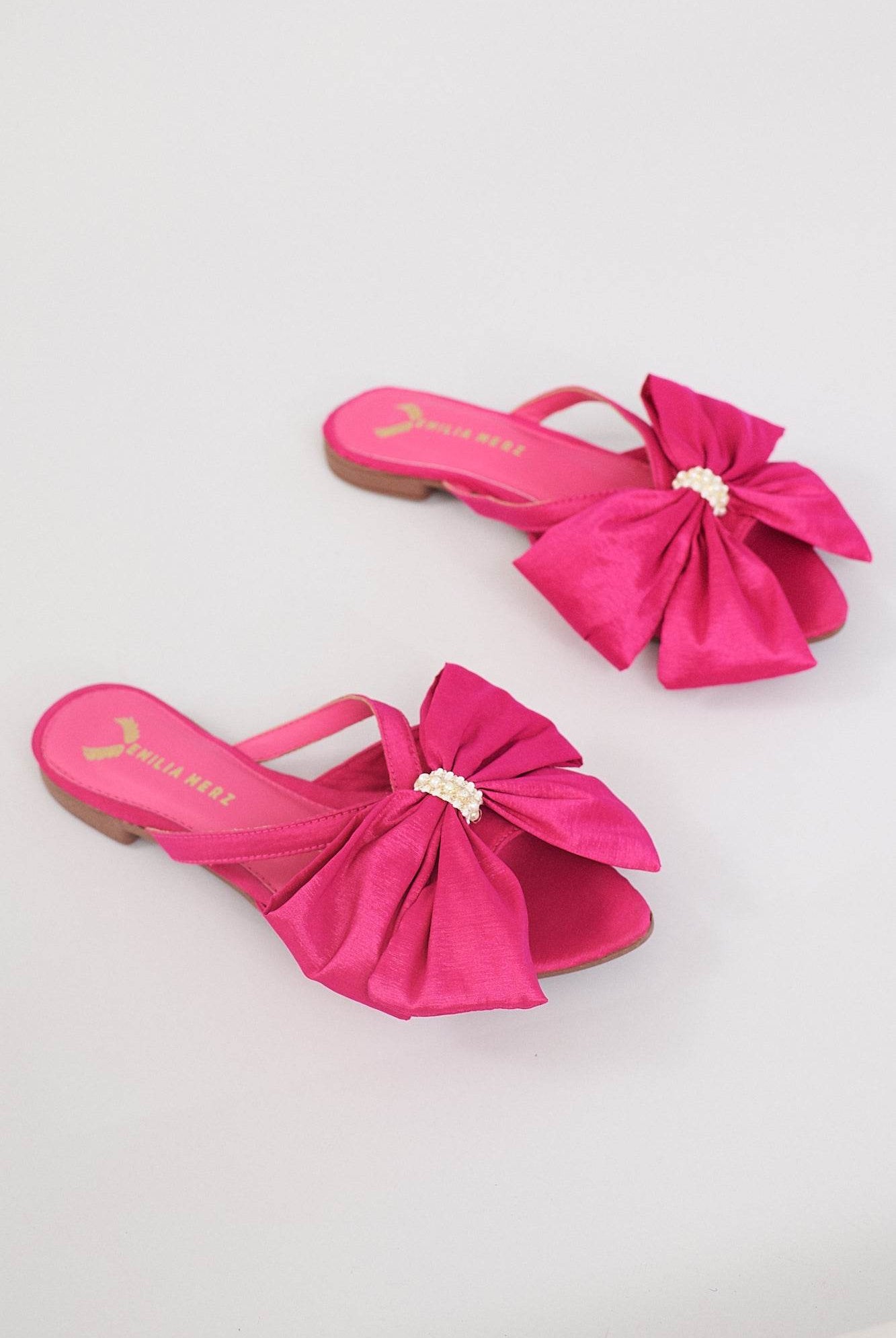 Pink summer slippers with large bow and pearl detail on light background