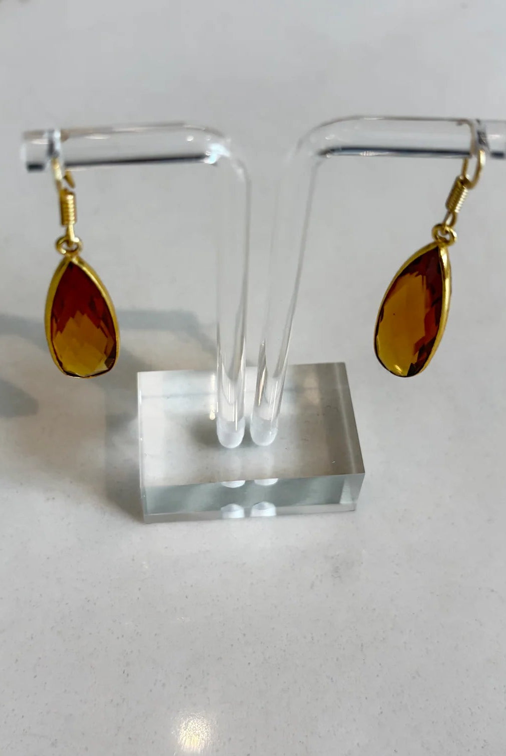 Close-up of the Aurea golden amber drop earrings, highlighting the detailed facets of the gemstone and the polished gold setting.