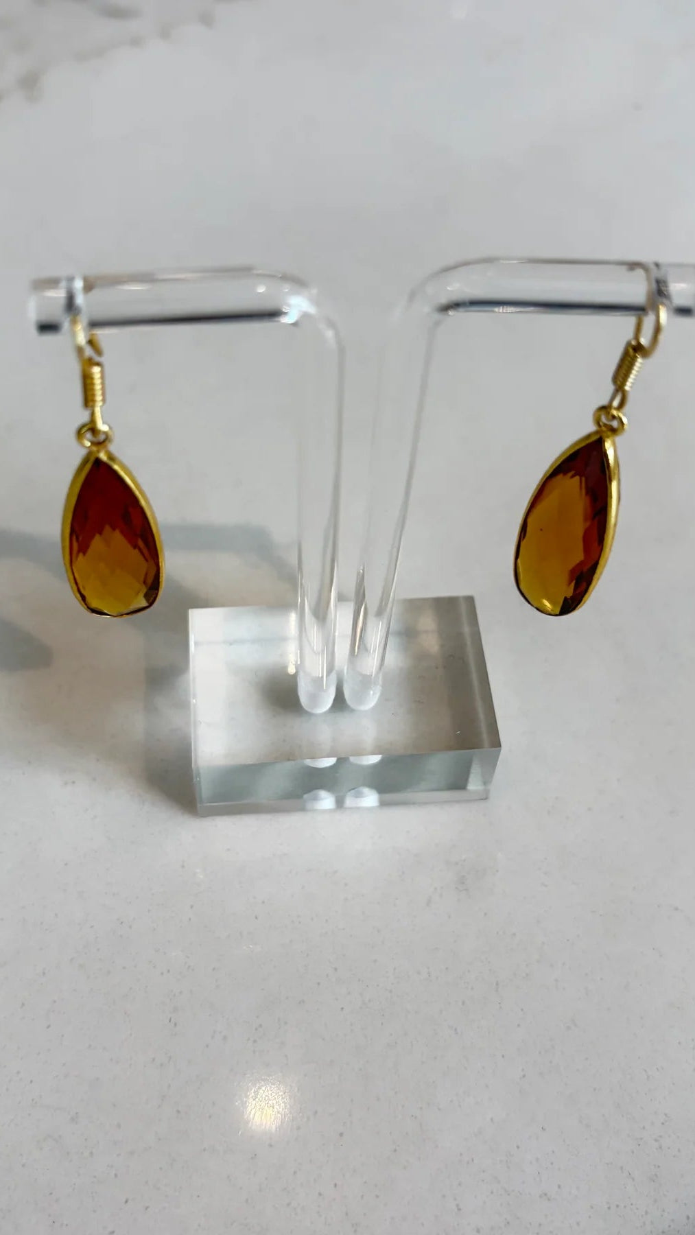 Close-up of the Aurea golden amber drop earrings, highlighting the detailed facets of the gemstone and the polished gold setting.