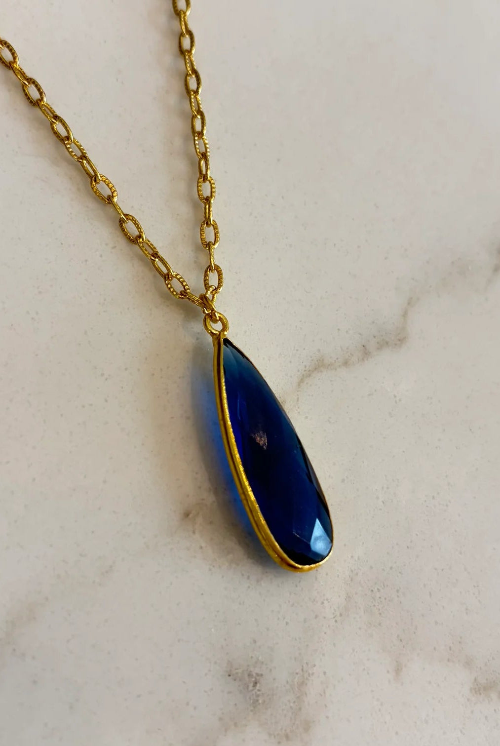 Close-up of the Aurea midnight blue statement necklace, highlighting the detailed facets of the gemstone and the polished gold setting.