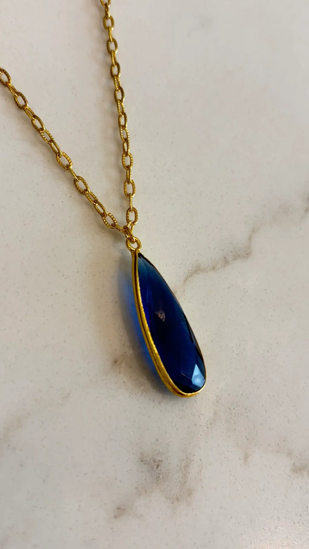 Close-up of the Aurea midnight blue statement necklace, highlighting the detailed facets of the gemstone and the polished gold setting.