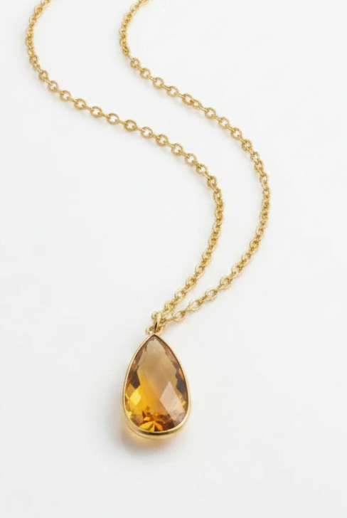 Emilia Merz Aurea statement necklace featuring a golden amber teardrop-shaped faceted stone set in 18K gold plating on a delicate chain.