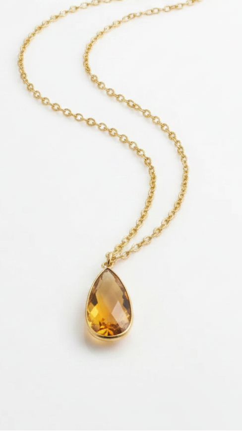 Emilia Merz Aurea statement necklace featuring a golden amber teardrop-shaped faceted stone set in 18K gold plating on a delicate chain.