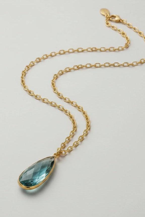 Emilia Merz Aurea statement necklace featuring a soft teal teardrop-shaped faceted stone set in 18K gold plating on a delicate chain.