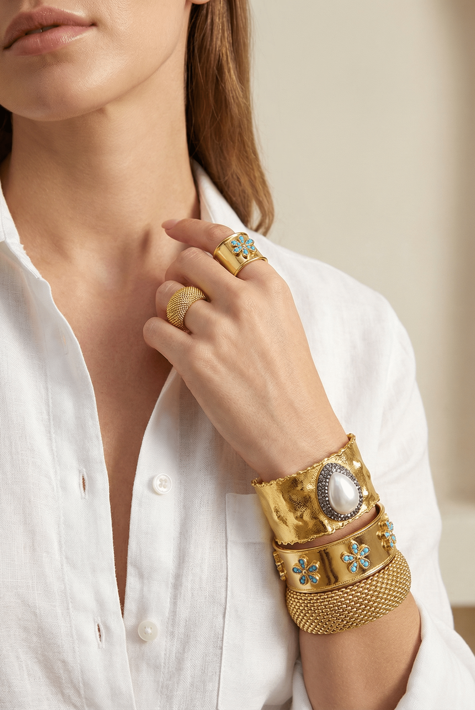 A set of Emilia Merz floral jewelry including an adjustable gold ring and open cuff with green gemstone details.