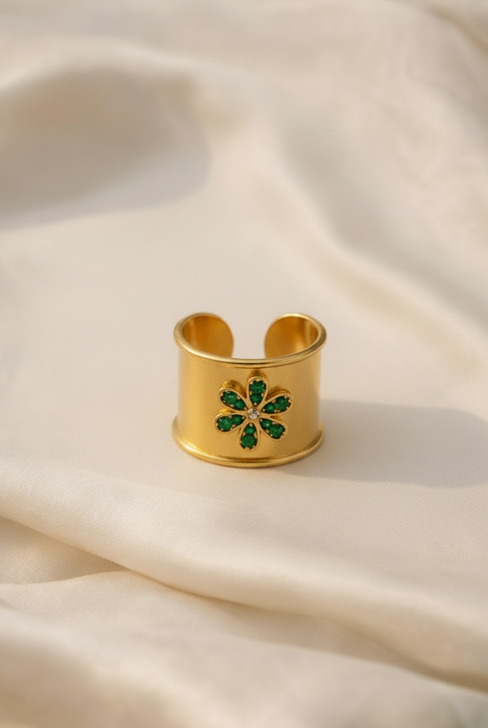 Emilia Merz Emerald Bloom Ring featuring a wide gold band and a vibrant green crystal flower motif.