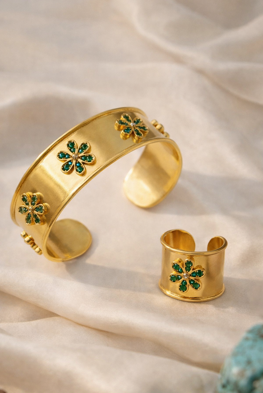 Close-up of the Emerald Bloom Ring and matching cuff bracelet, highlighting the 18K gold plating and emerald stones.