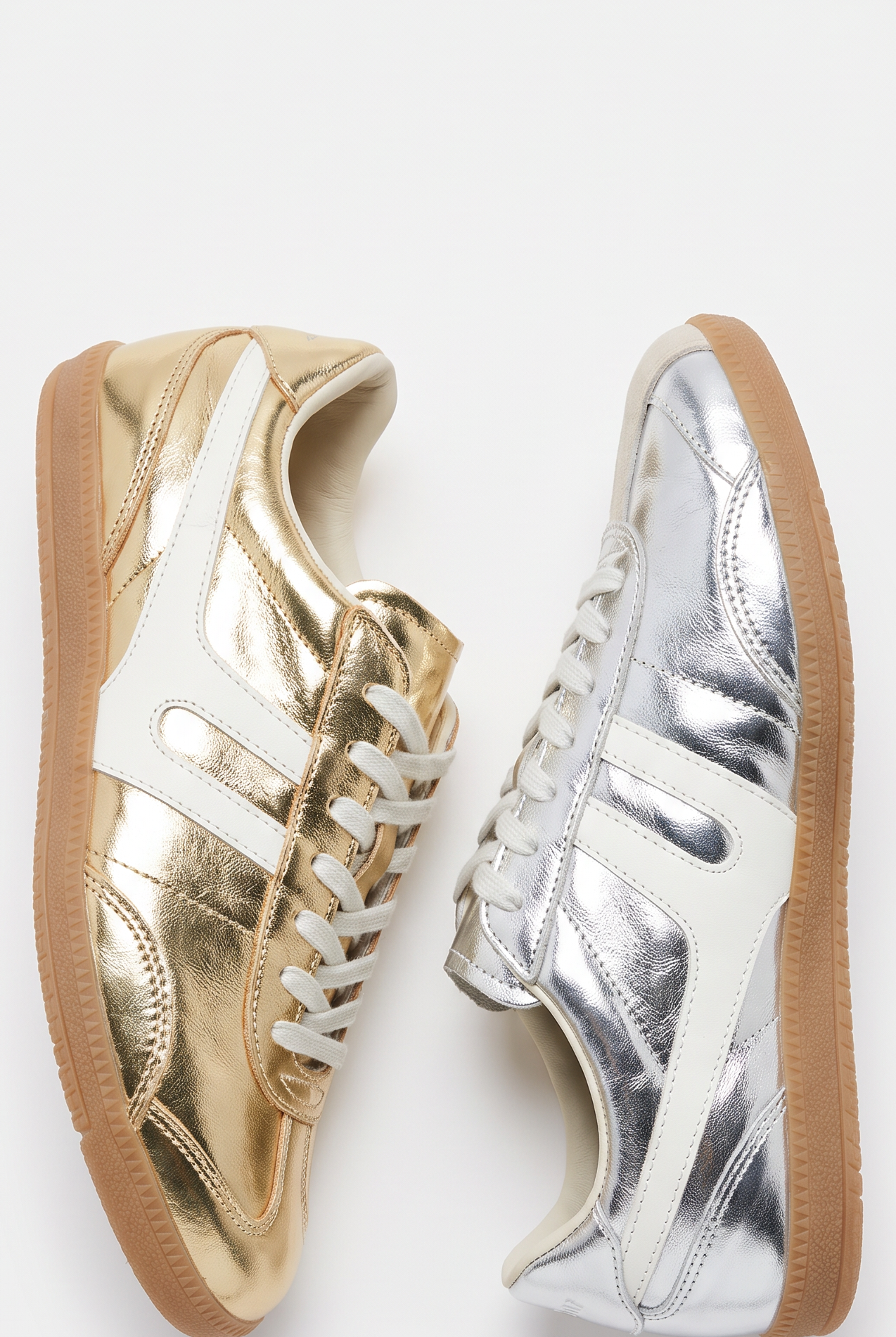 Two low-top sneakers shown side by side on a white background: one metallic gold and one metallic silver, both with white side stripes, white laces, and gum soles.