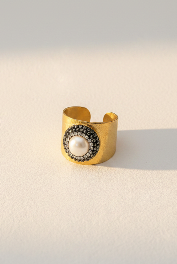 Emilia Merz Midnight Pearl Ring featuring an 18K gold-plated wide band and a central pearl with a dark crystal halo.