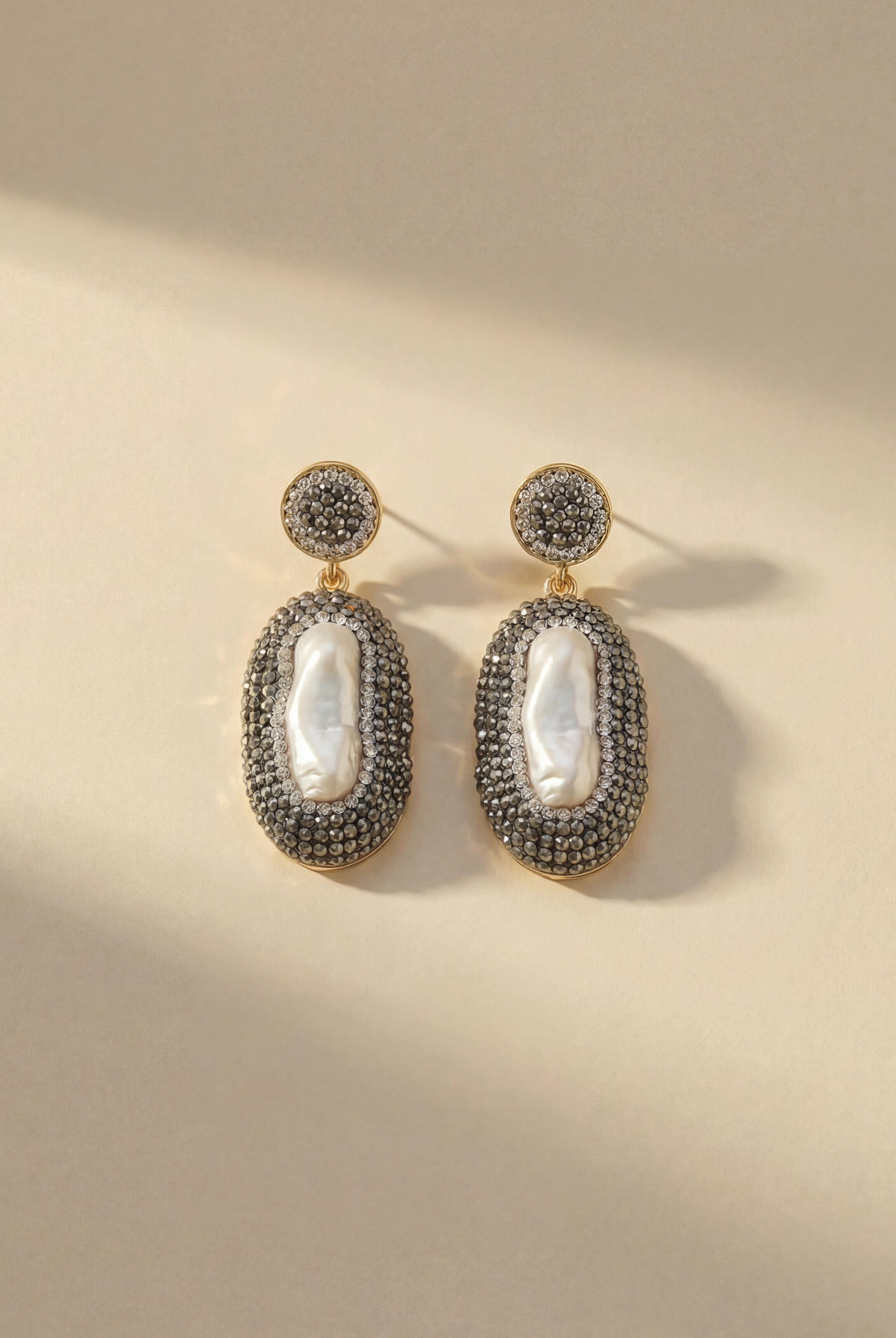 The Celestial Pearl Drop Earrings displayed against a neutral background, highlighting the contrast between the white pearls and golden settings.