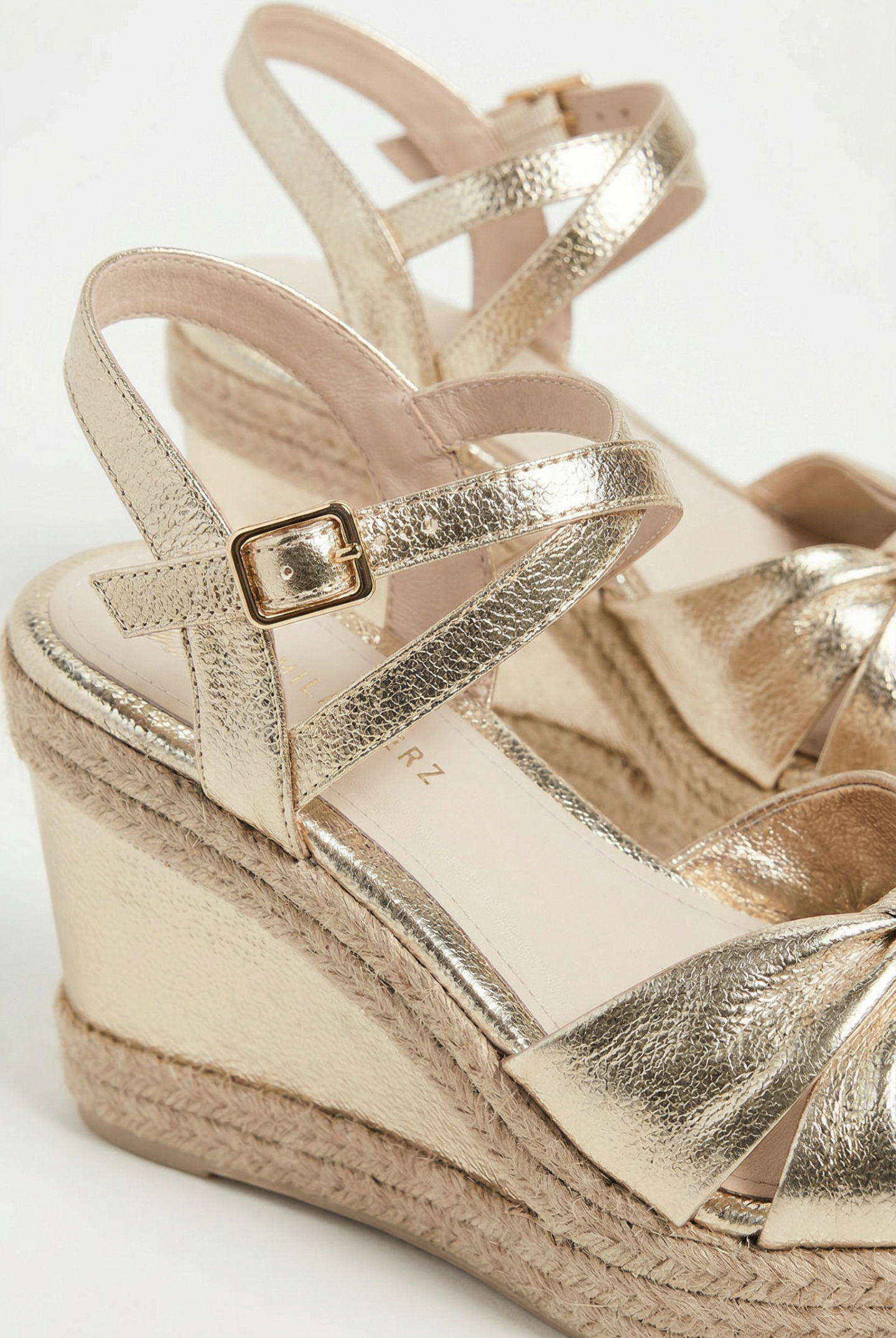 Gold wedge sandal with espadrille sole on a white background