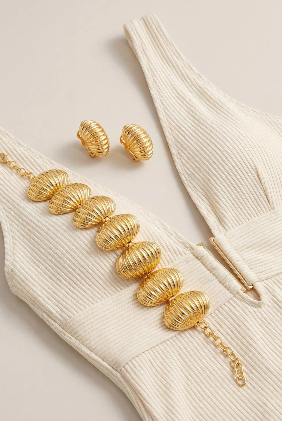 Close-up of the Marbella Shell Bracelet and earrings highlighting the sculptural texture and radiant gold finish against a summer outfit.