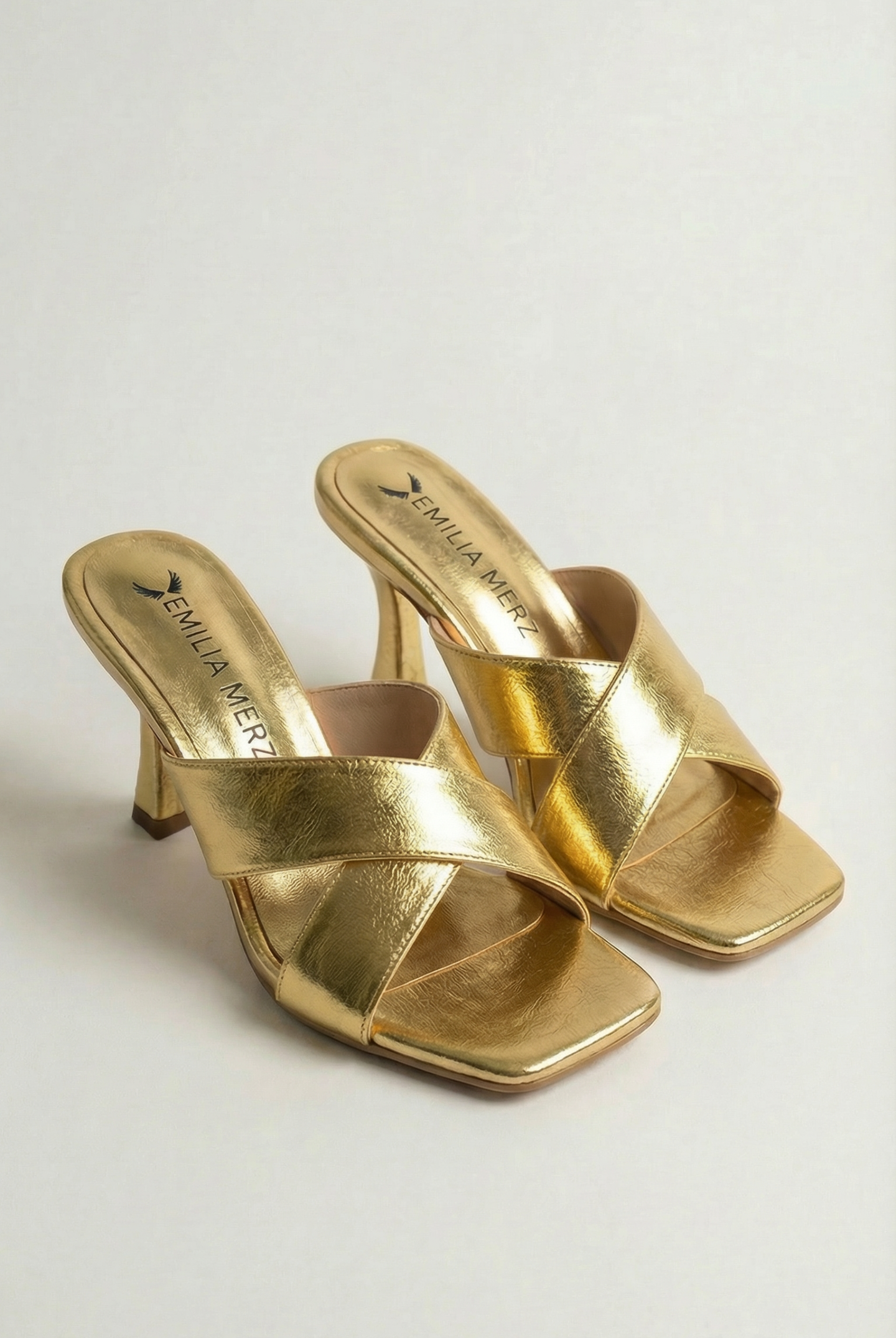 Gold high-heeled sandals on a light gray background