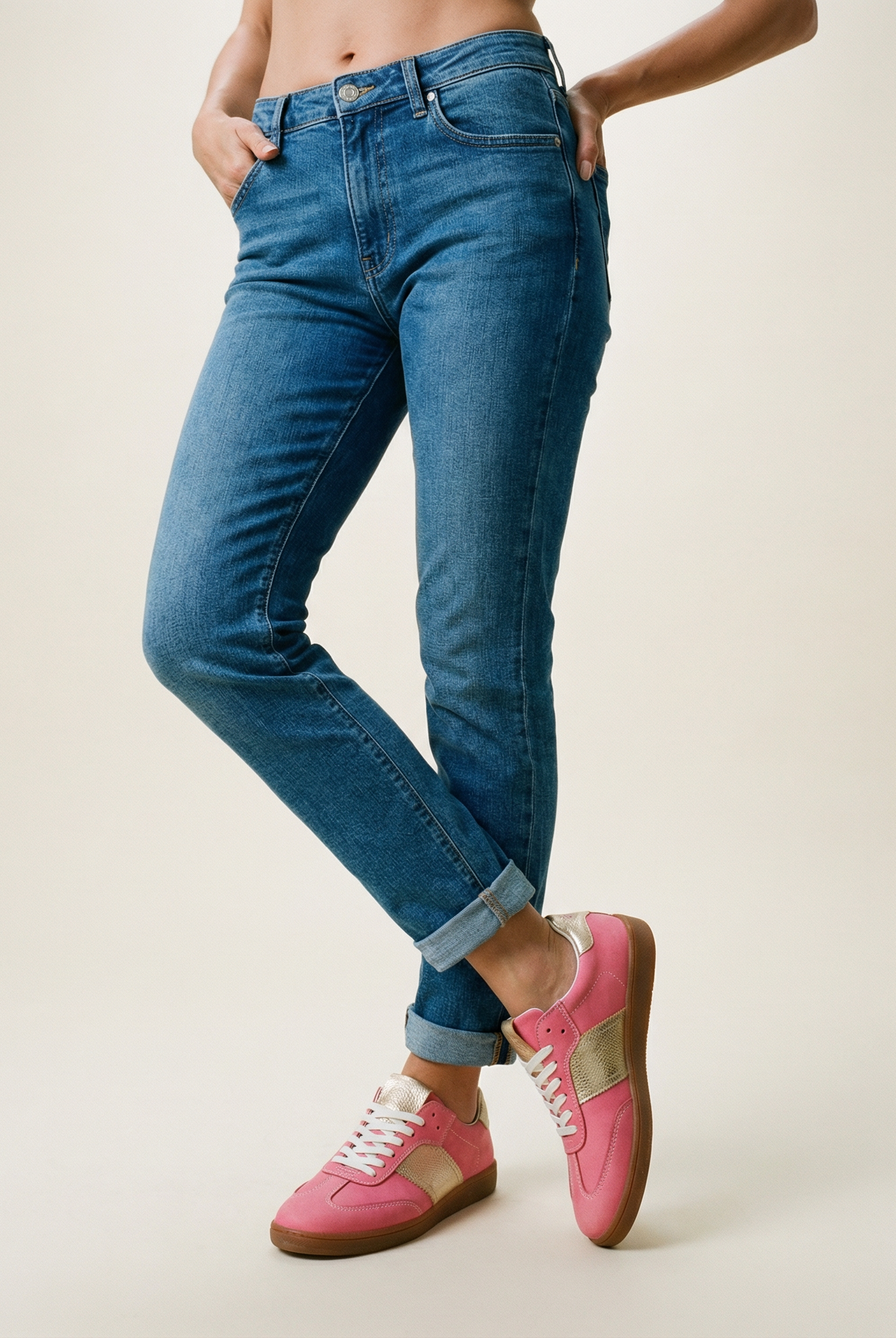 Person wearing blue jeans and pink sneakers on a plain background