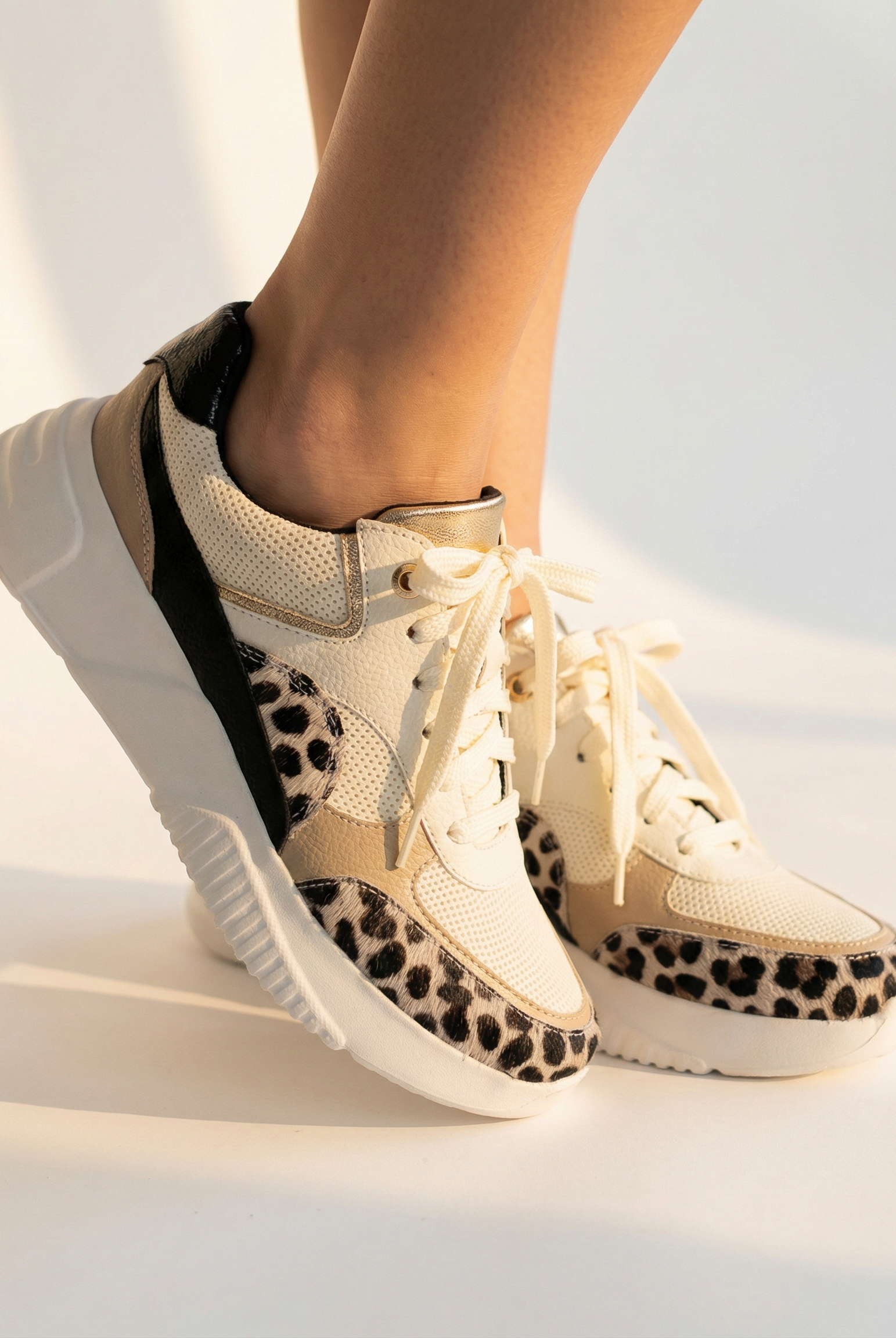 Beige sneakers with leopard print accents worn by a person on a light background