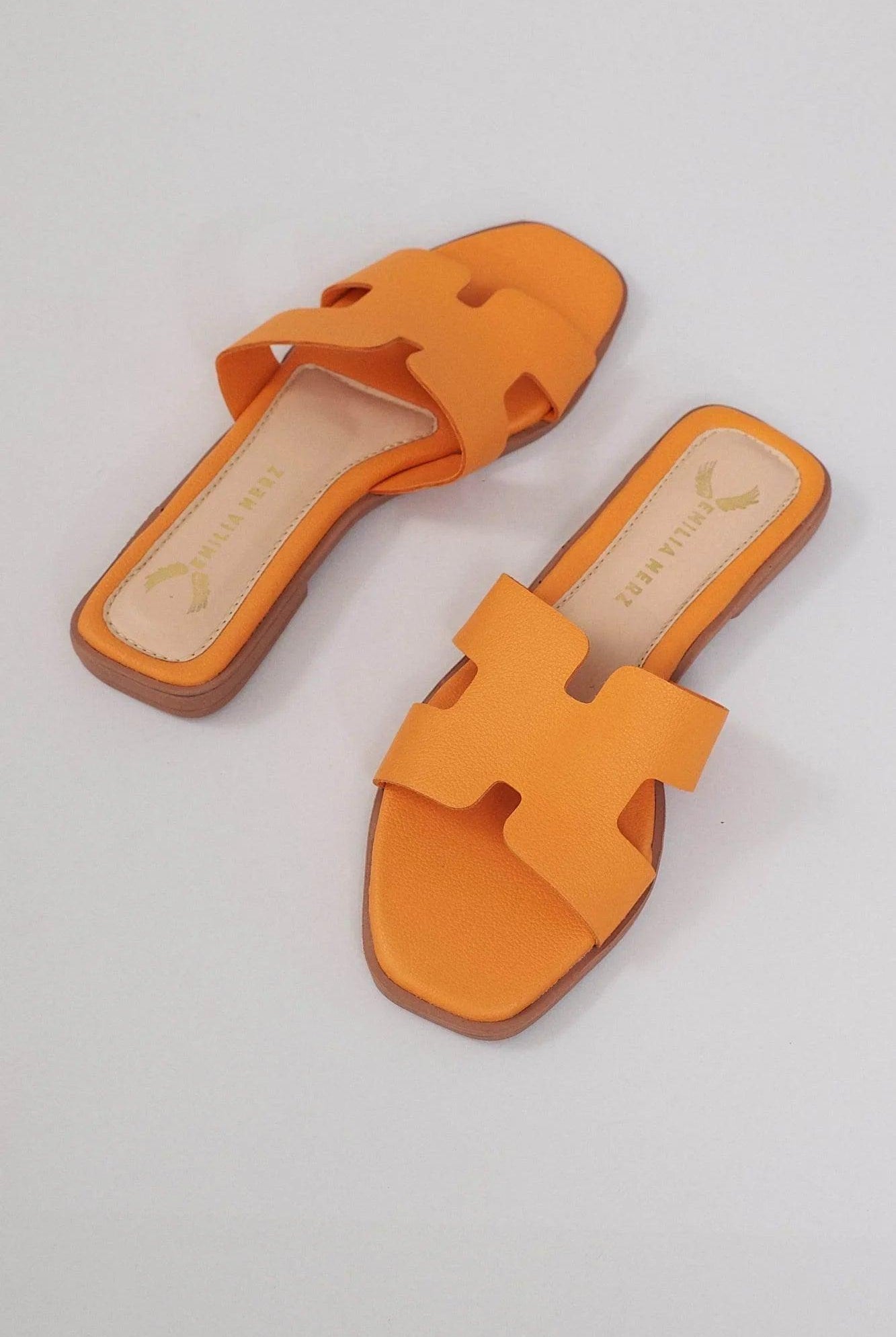 Orange flat slide sandals with cushioned sole and cut-out strap design on light background