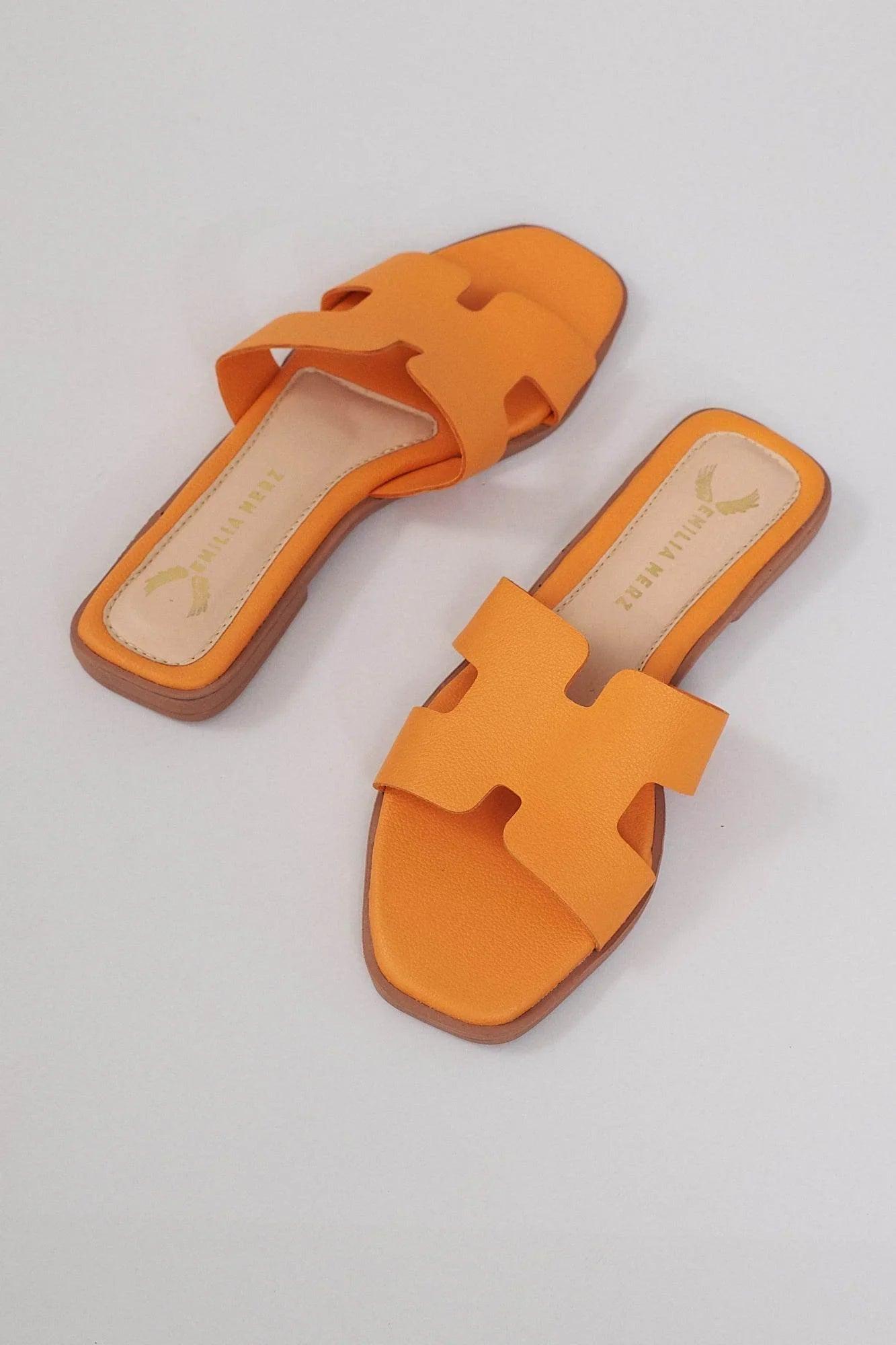 Orange flat slide sandals with cushioned sole and cut-out strap design on light background