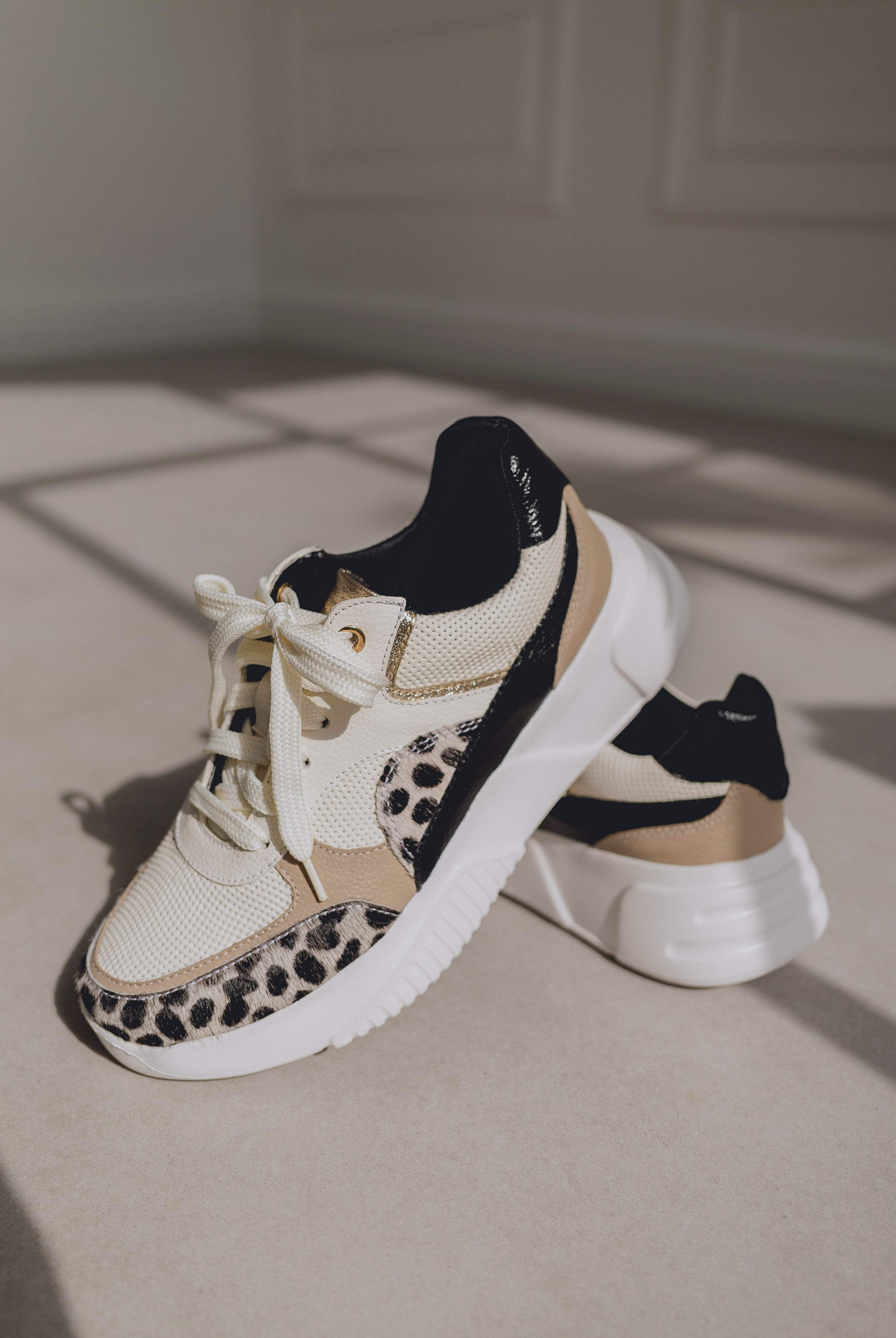 Pair of sneakers with leopard print details on a neutral background