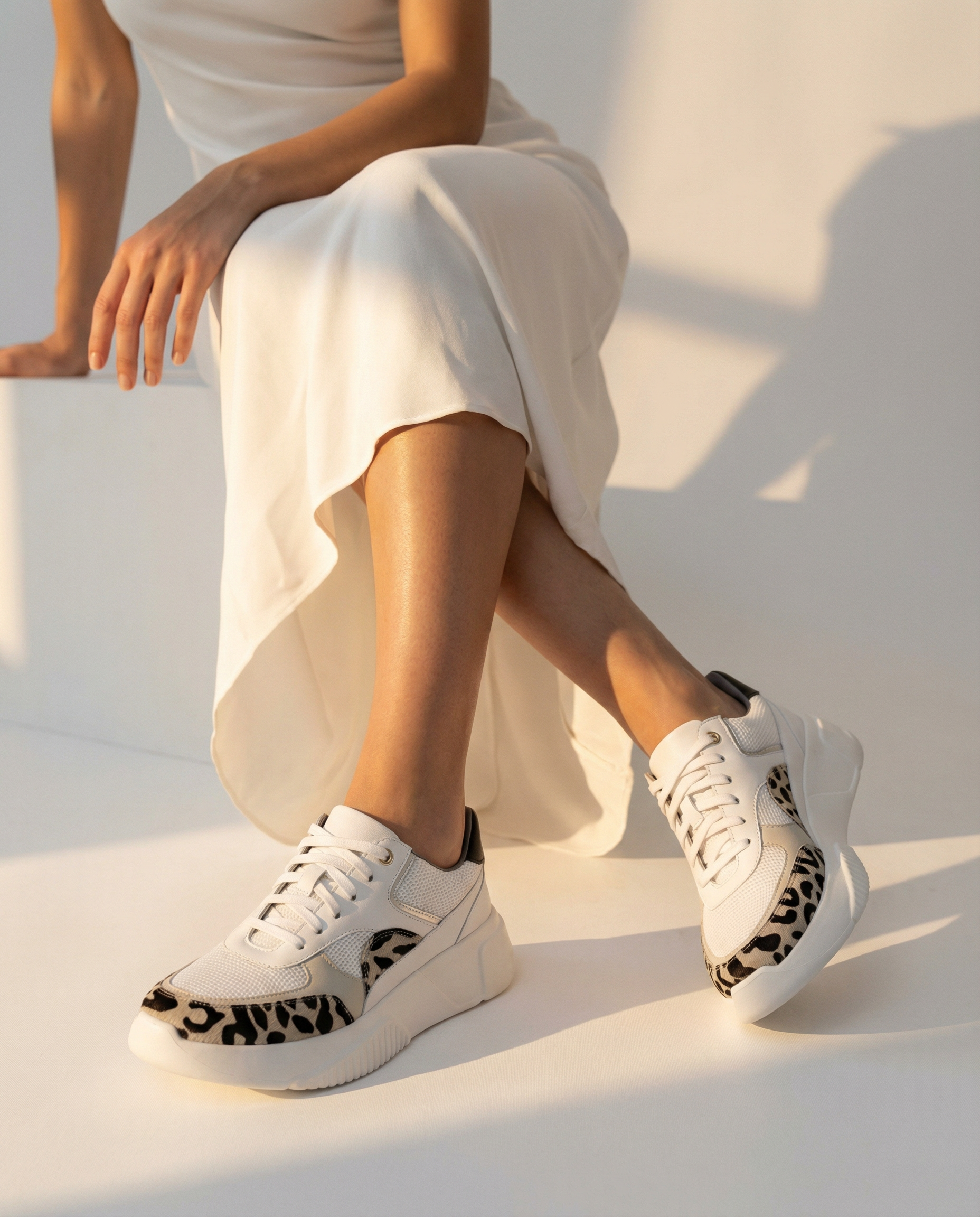 Person wearing white sneakers with leopard print details on a white surface