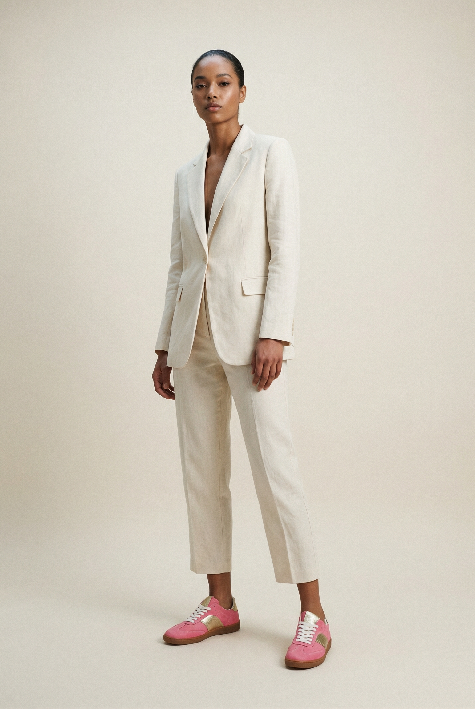 Person wearing a white suit with pink sneakers on a plain background