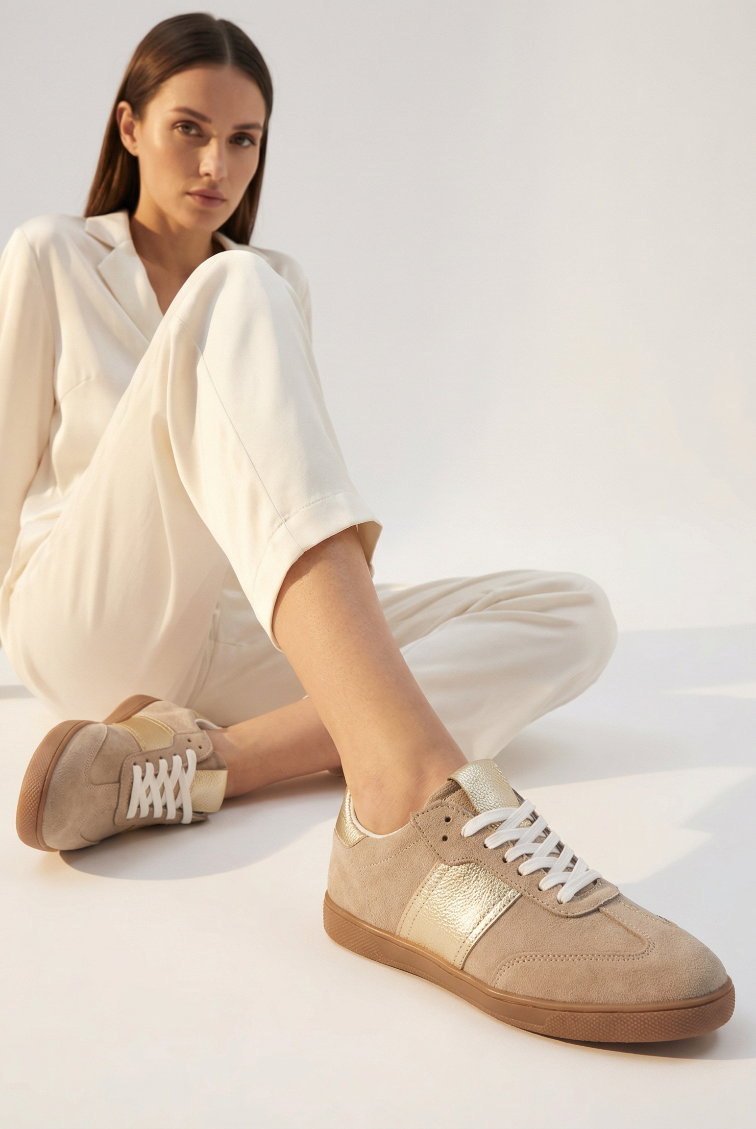 Woman wearing beige sneakers with a white background