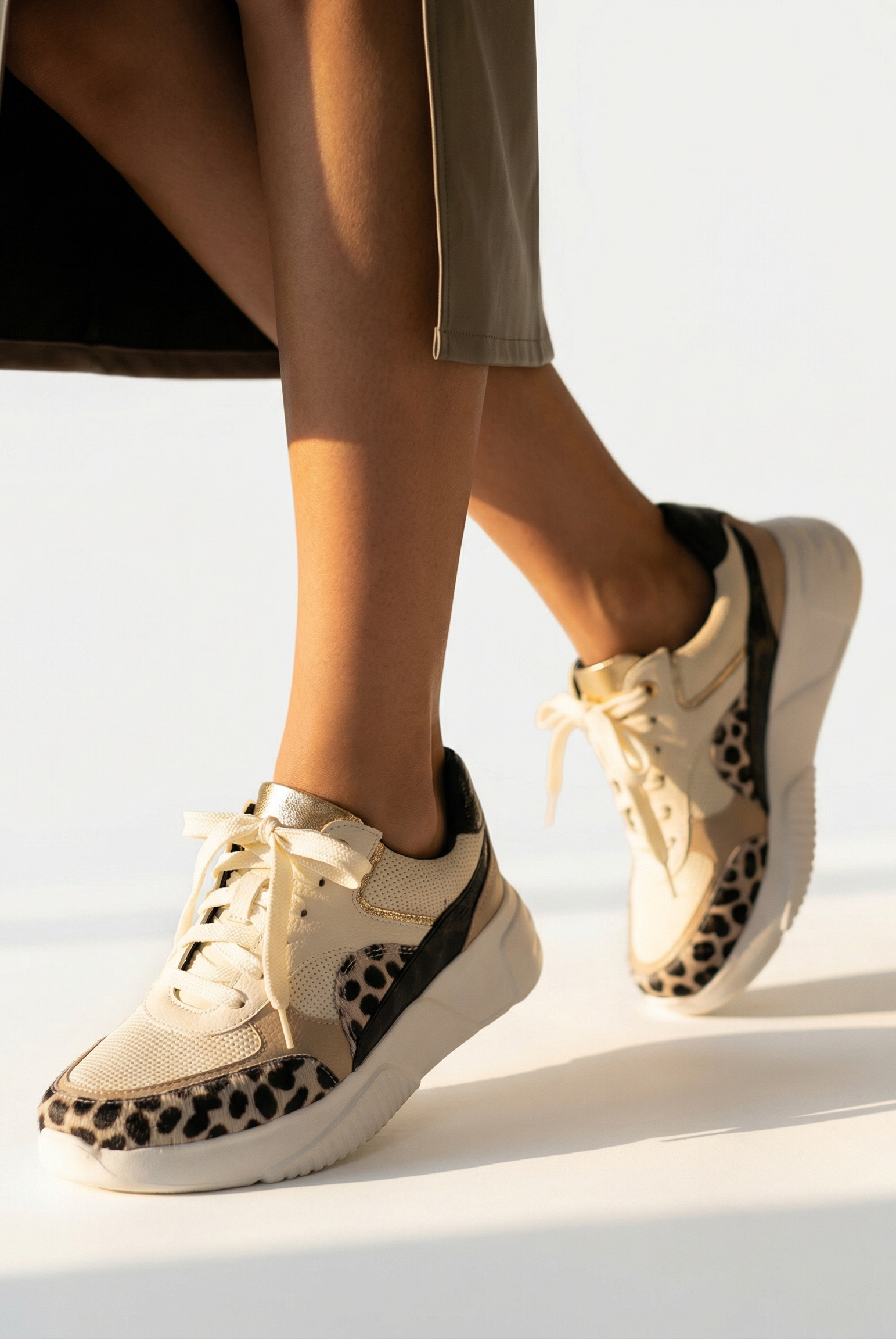 Person wearing beige sneakers with leopard print details on a white background