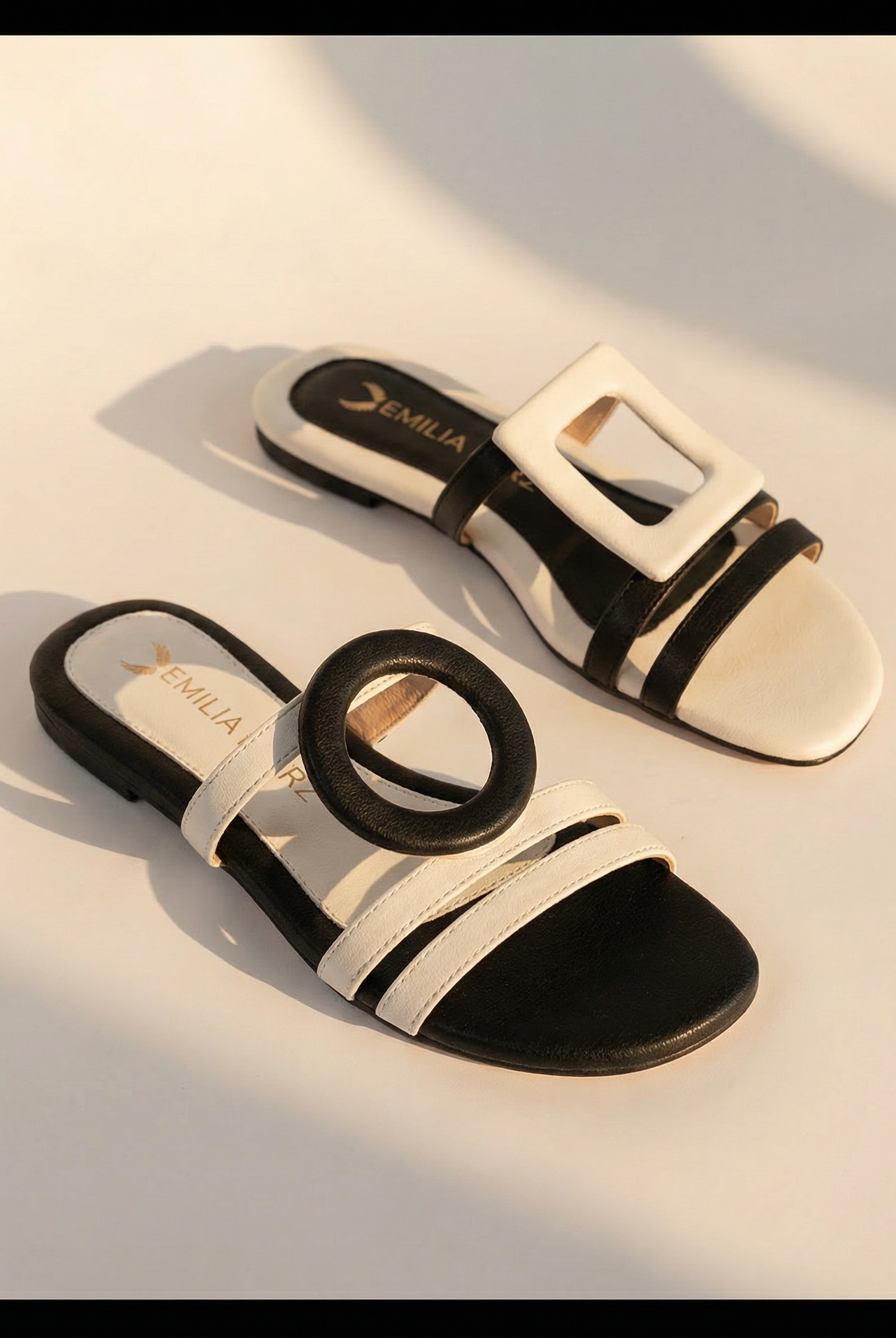 Black and white sandals with emilia merz logo on a light background
