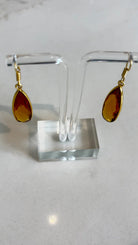 Close-up of the Aurea golden amber drop earrings, highlighting the detailed facets of the gemstone and the polished gold setting.