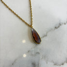 Close-up of the Aurea deep violet pendant necklace, highlighting the detailed facets of the gemstone and the polished gold setting.