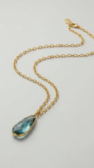 Emilia Merz Aurea statement necklace featuring a soft teal teardrop-shaped faceted stone set in 18K gold plating on a delicate chain.
