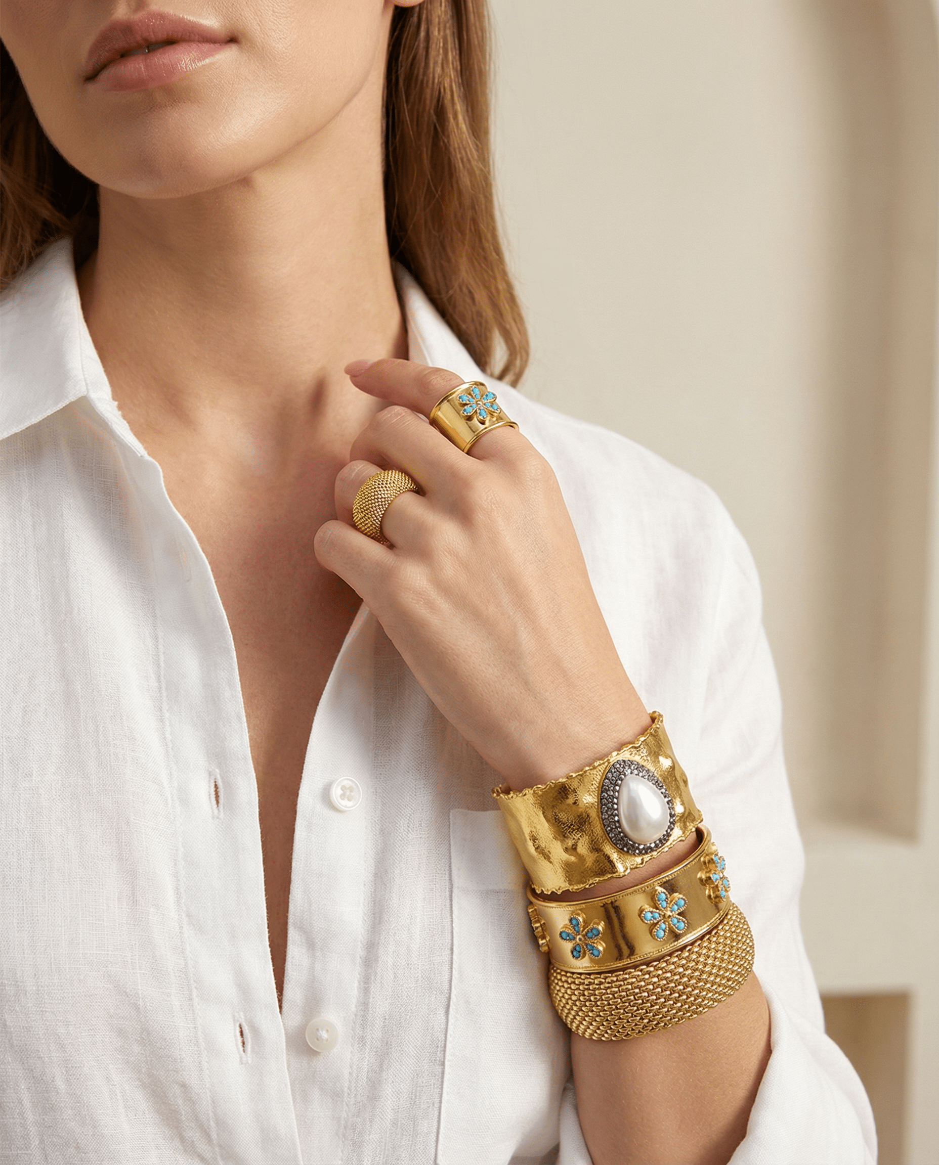 A set of Emilia Merz floral jewelry including an adjustable gold ring and open cuff with green gemstone details.