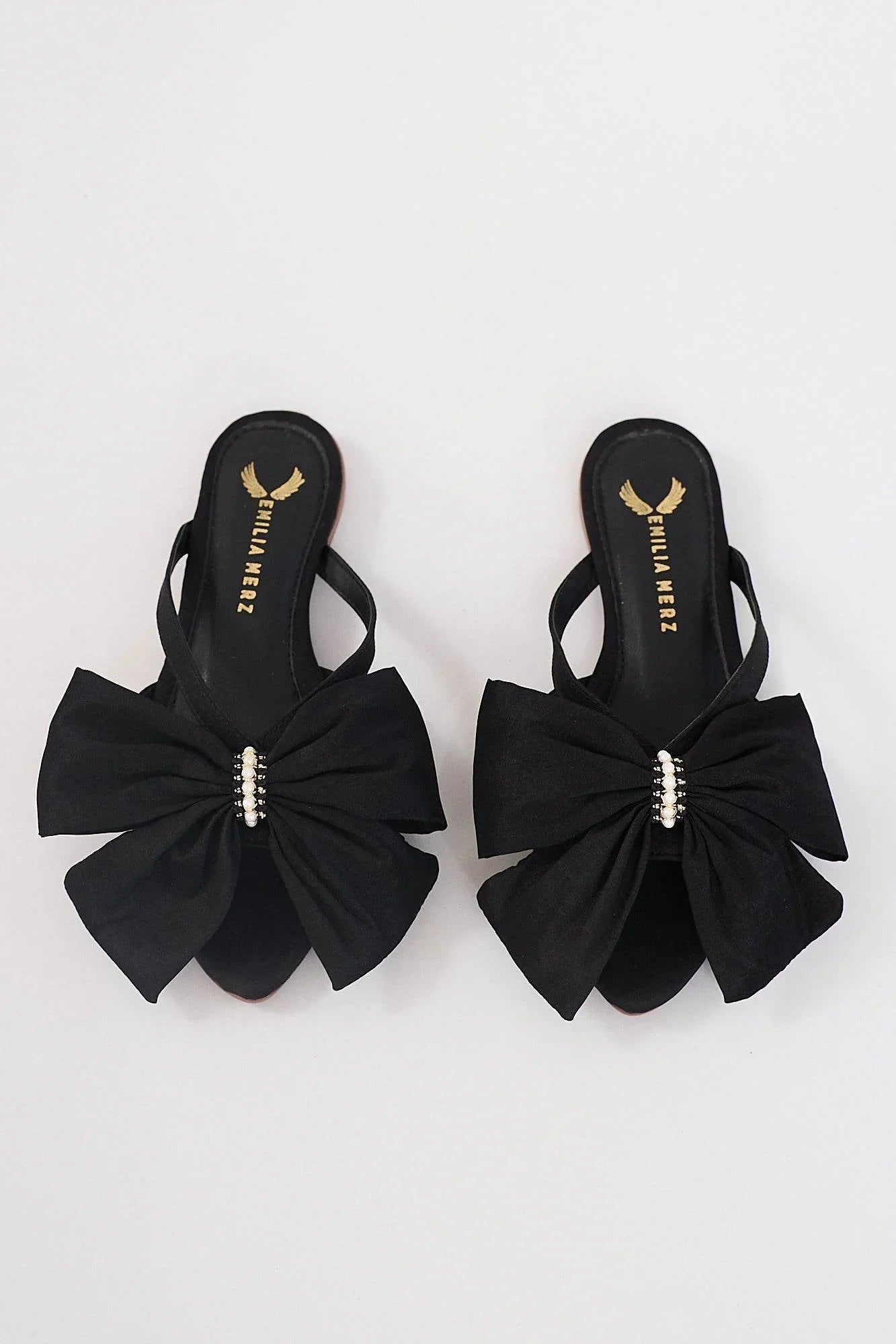 Comfortable black flat sandals for women with statement bow and pearl detailing.