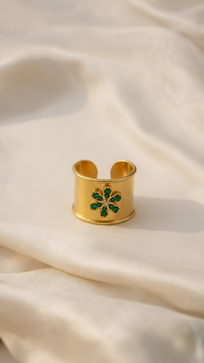 Emilia Merz Emerald Bloom Ring featuring a wide gold band and a vibrant green crystal flower motif.