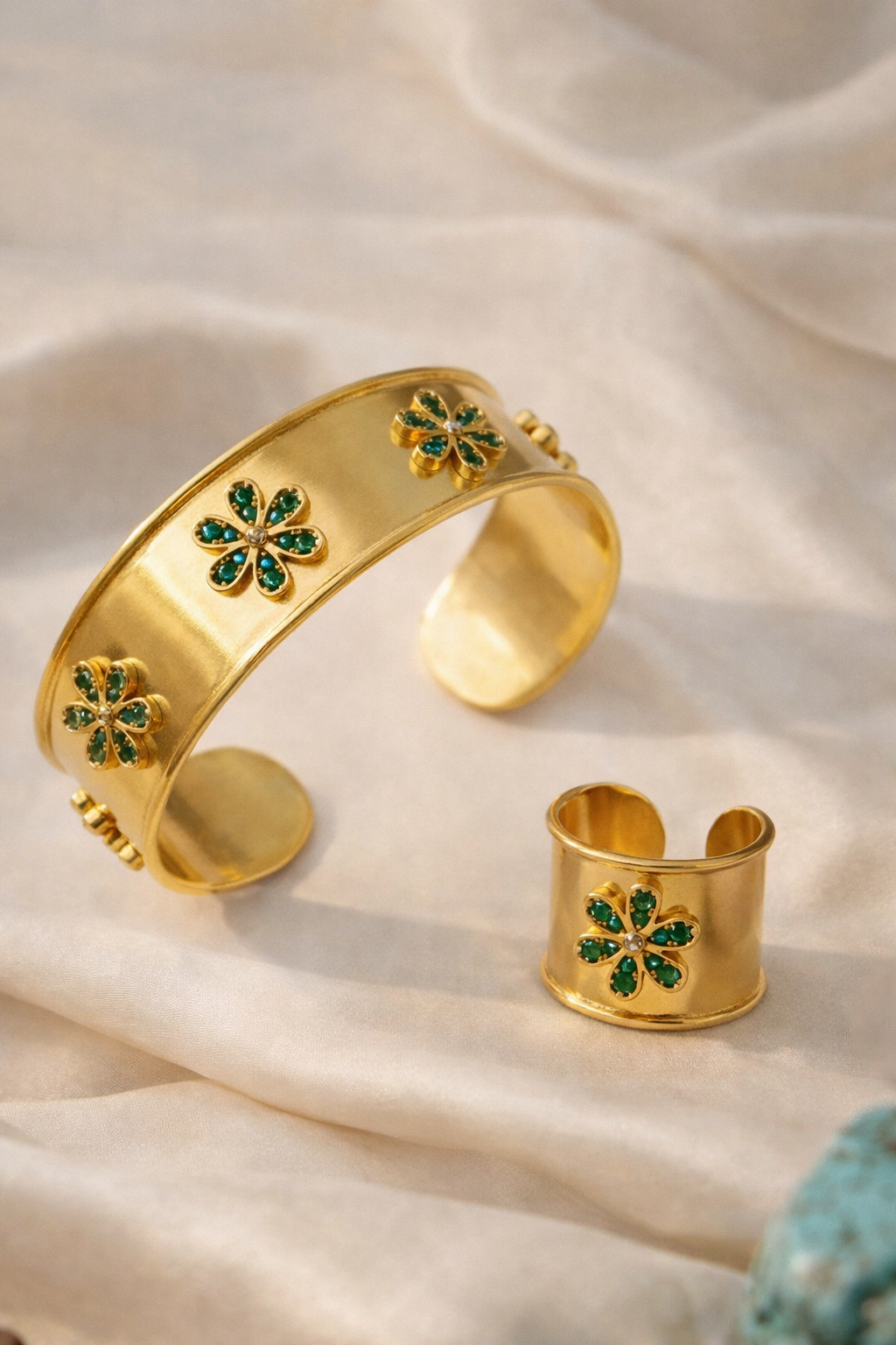 Close-up of the Emerald Bloom Ring and matching cuff bracelet, highlighting the 18K gold plating and emerald stones.