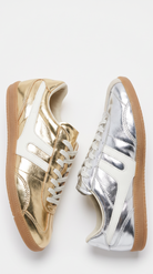 Two low-top sneakers shown side by side on a white background: one metallic gold and one metallic silver, both with white side stripes, white laces, and gum soles.