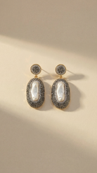 The Celestial Pearl Drop Earrings displayed against a neutral background, highlighting the contrast between the white pearls and golden settings.