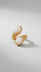 Emilia Merz Serpenté Lumina ring featuring a sculptural gold wrap design with light-toned faceted stones, worn on a model.
