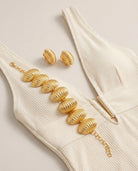 Close-up of the Marbella Shell Bracelet and earrings highlighting the sculptural texture and radiant gold finish against a summer outfit.
