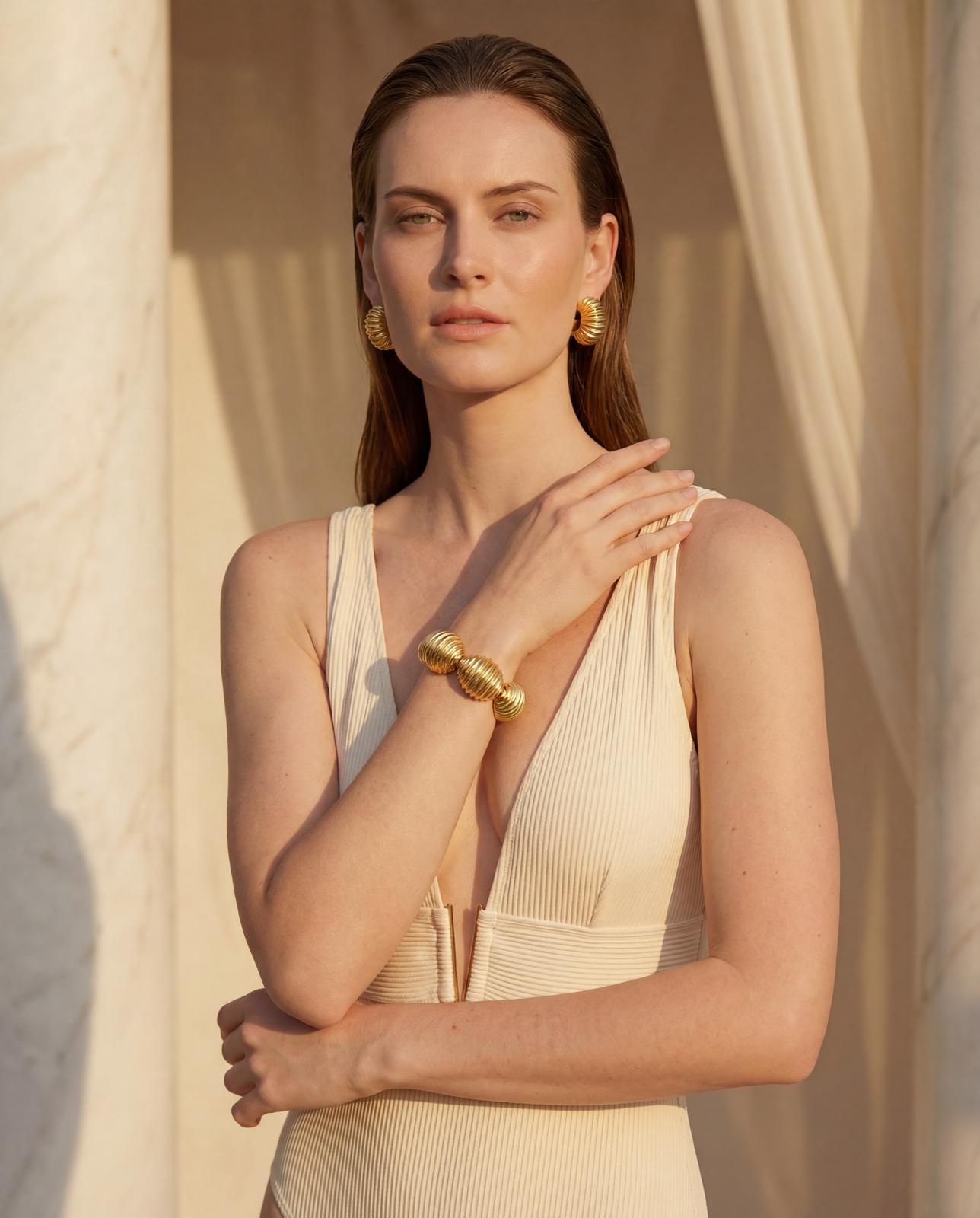 Emilia Merz Marbella Shell Bracelet featuring three large, ribbed 18K gold-plated shell links worn on a model's wrist.