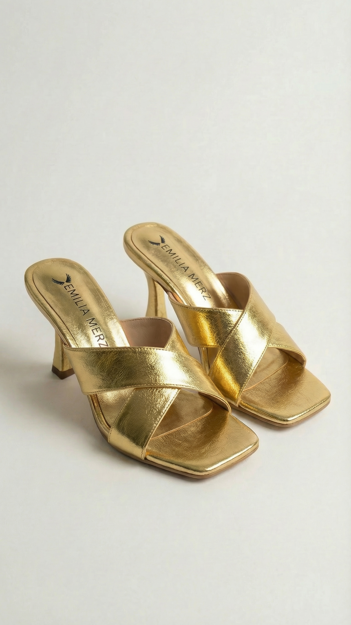 Gold high-heeled sandals on a light gray background