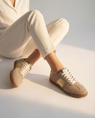 Person wearing beige sneakers with white laces on a light background
