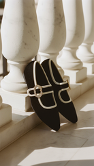 Black ballet flats with gold buckles on a marble staircase