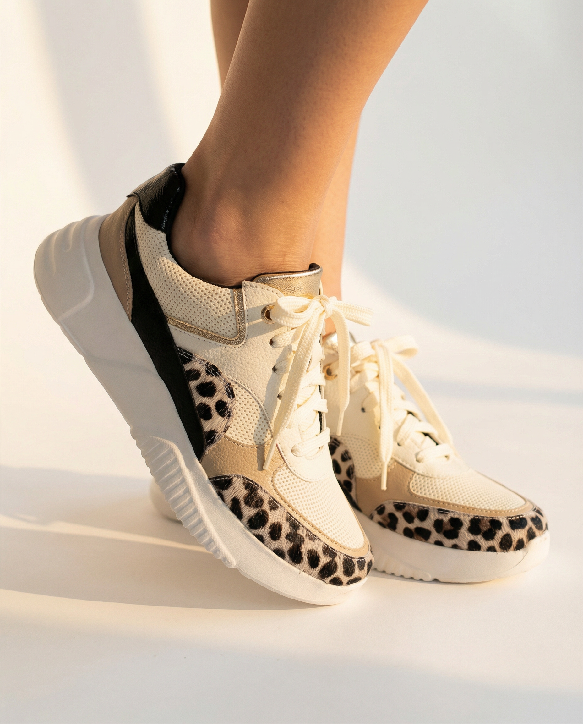 Beige sneakers with leopard print accents worn by a person on a light background