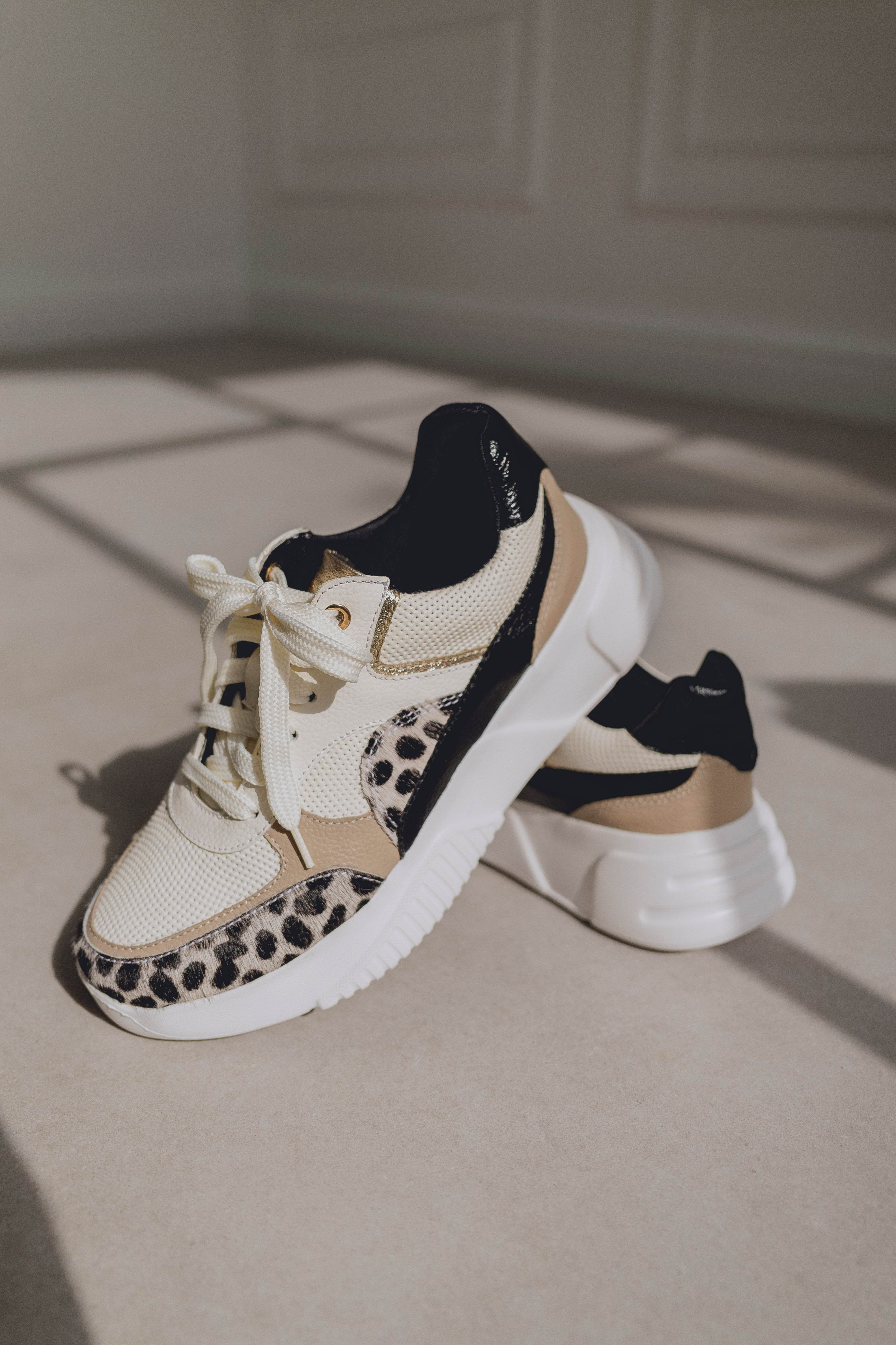 Pair of sneakers with leopard print details on a neutral background