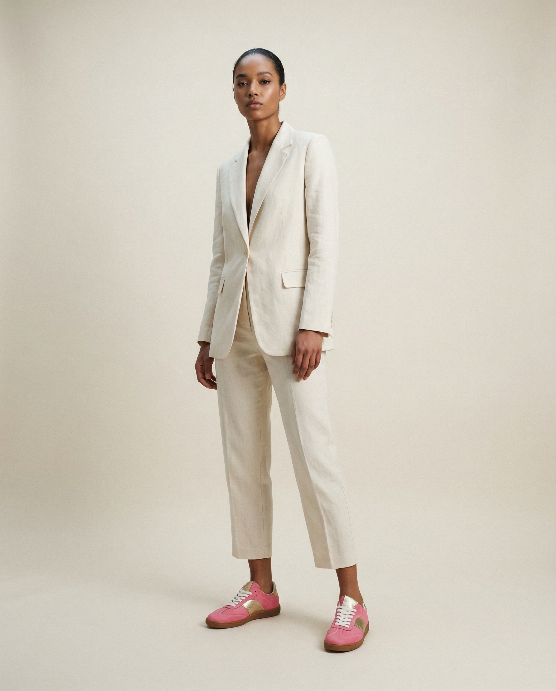 Person wearing a white suit with pink sneakers on a plain background