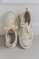 Pair of white sneakers with gold accents on a light background
