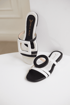 Black and white sandals on a white surface with a neutral background
