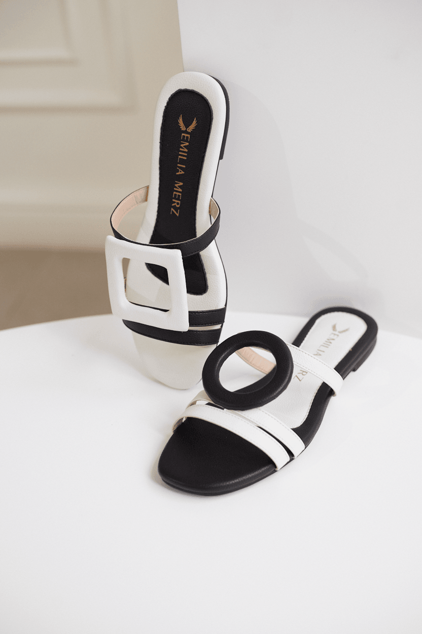 Black and white sandals on a white surface with a neutral background