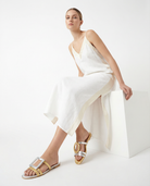 Woman wearing a white dress and gold silver sandals on a white background